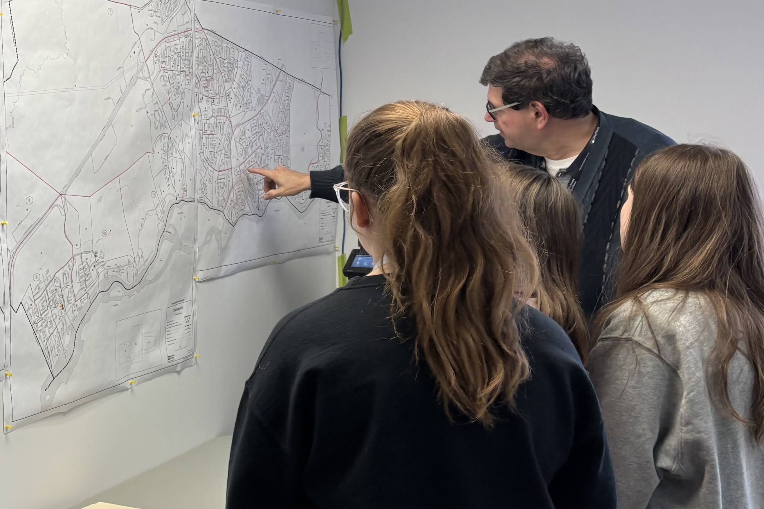 Des jeunes accompagnés du directeur du scrutin devant une carte.